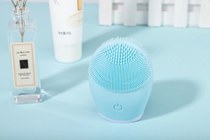 Detail view of sky blue silicone facial cleanser with soft bristles and power button