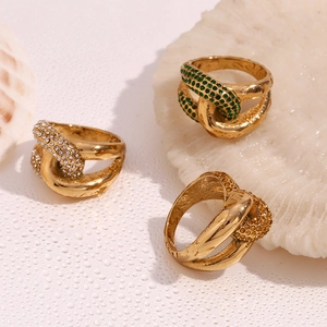 Detailed shot of gold-plated knot rings with green and amber zircons on shells