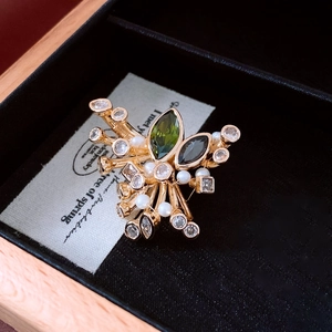 Close-up of French vintage brooch with green gemstone and pearls on a jewelry card
