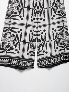 Détail du pantalon large présentant des imprimés floraux vintage noir et blanc avec bordures
