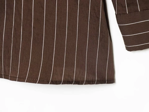 Detailed close-up of dark brown striped shirt featuring refined hem and sleeve cuff texture