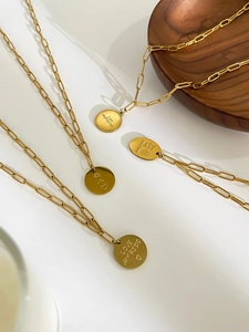 Close-up of engraved gold titanium steel pendants with inspirational text on link chains