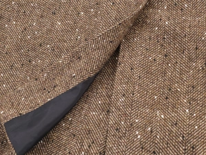 Gros plan du tissu en tweed à chevrons marron avec mouchetures et doublure en soie noire