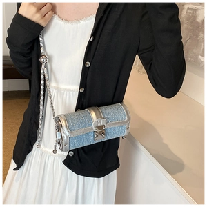 Detail of blue denim cylinder bag with rhinestone embellishments and silver chain strap