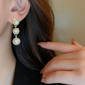 Detailed view of elegant gold drop earrings with sparkling rhinestones and white pearls