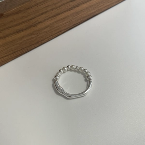 Macro detail of silver beaded ring with irregular smooth band on walnut wood surface