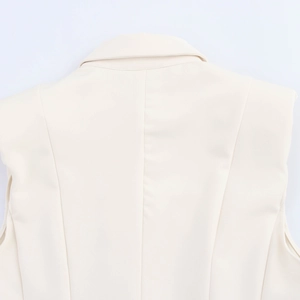 Detail view of the back shoulder seams and collar on a cream sleeveless blazer dress