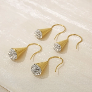 Detailed macro view of gold cone drop earrings with white crystal pave on silk