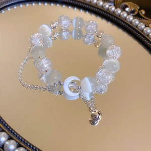 Close-up of cat eye stone moon bracelet on a pearl mirror tray with detailed silver charms