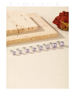 Detail of eight lavender fireworks-cut silver stud earrings in various sizes on stone