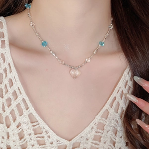 Close-up of beach style beaded necklace with blue glass beads and clear heart pendant