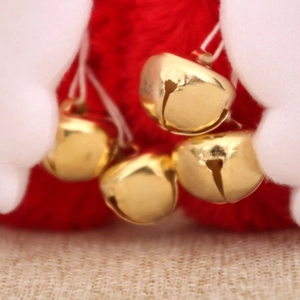 Detailed view of festive golden bells on red plush fabric for Christmas earmuffs decoration