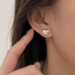Macro shot of a 925 sterling silver heart-shaped earring with a bow relief detail