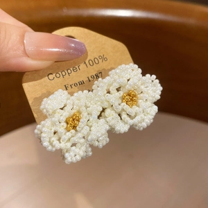Detailed view of handmade camellia beaded flower earring with copper base and white pearls