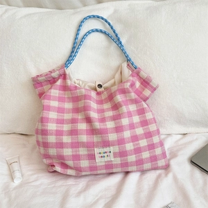 Detailed close-up of pink and white checkered tote bag with blue rope handle on bed