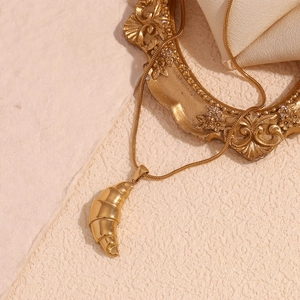 Detailed view of 18K gold plated croissant pendant hanging on vintage carved photo frame