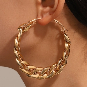 Gros plan de boucles d'oreilles créoles à gros maillons dorés montrant la texture du métal