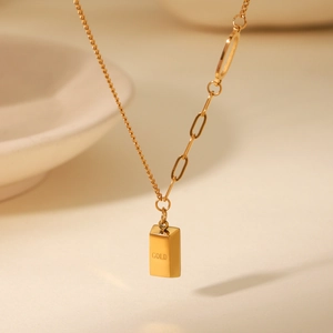 Macro view of 18K gold bar pendant necklace with GOLD engraving and paperclip chain