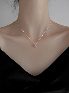 Close-up of a minimalist s925 silver teardrop pendant necklace worn on a woman's neck