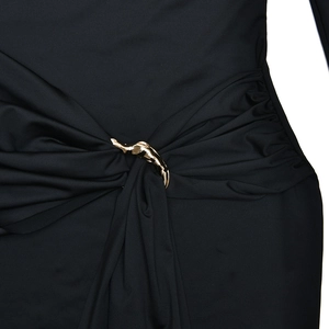 Detailed close-up of gold metal waist buckle on a black long sleeve knit dress