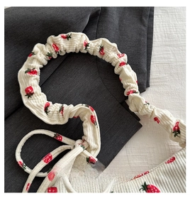 Detail of white corduroy tote bag with red strawberry patterns and soft ruched handle