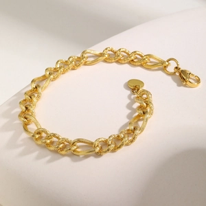 Detailed macro view of 18K gold plated Figaro chain bracelet with engraved texture
