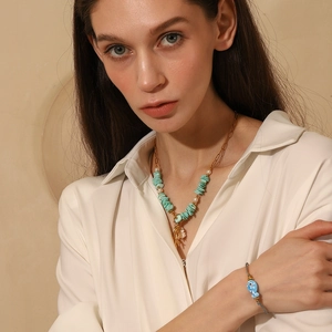 Close-up of model wearing 18K gold clip chain necklace with turquoise and pearl charms