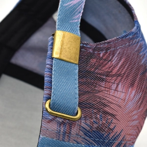 Detail of adjustable bronze metal buckle on palm leaf print tie-dye baseball cap