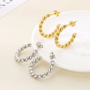 Détail des boucles d'oreilles créoles torsadées en C en acier poli doré et argenté