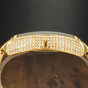 Macro side view of gold-tone tonneau watch case fully iced out with white diamonds