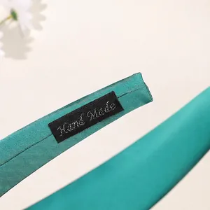 Peacock green satin wide headband with handmade woven label showing fine stitching