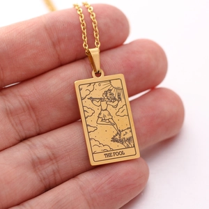 Macro detail of golden tarot card pendant featuring The Fool design on a long chain