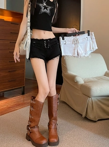 Dettaglio degli shorts in denim vintage con occhielli laterali stringati e orlo a frange