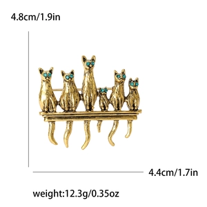 Vintage gold alloy brooch with six cats and green gem eyes on a white background