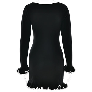 Detail of black long sleeve dress with white ruffled hem and contrasting trim design