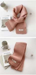 Close-up of pink knitted winter scarf with a small logo label on a white table