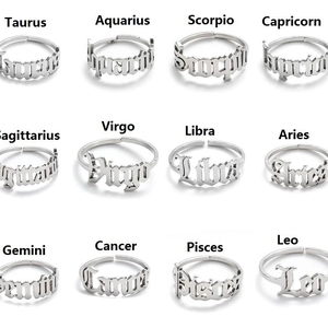 Set of 12 zodiac stainless steel open rings with vintage cutout lettering on white background
