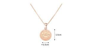Detail of rose gold circle pendant featuring scales relief and Justice engraving