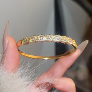 Detailed close-up of gold-plated geometric scale bangle with sparkling cubic zirconia