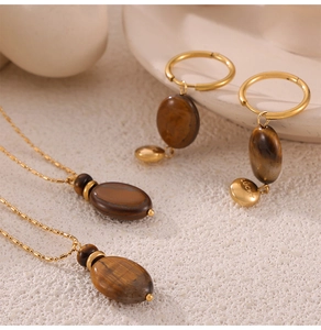 Detail of tiger eye stone pendant and golden bead chain jewelry set with lucky engraving