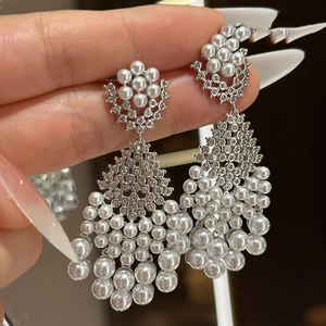 Macro close-up showing intricate silver metal tassels and white pearls on the earring