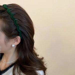 Detail view of wavy dark green velvet headband with inner teeth for volume and grip