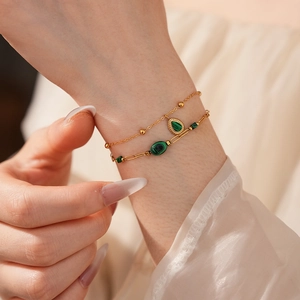Gros plan d'un bracelet double couche doré avec pendentifs en malachite verte au poignet