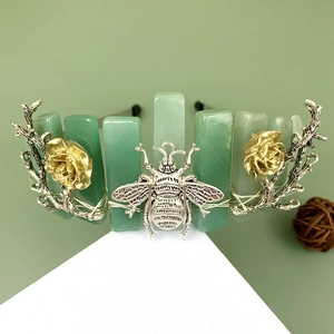 Detailed view of green crystal crown featuring silver bee and golden rose metal flowers