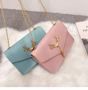 Close-up of pink and blue PU leather crossbody bags with golden deer head hardware