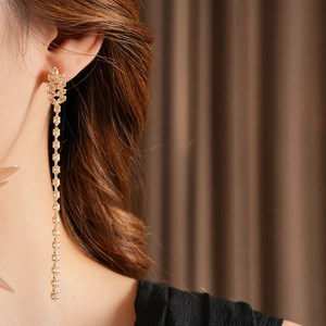 Elegant gold leaf earring with long cubic zirconia tassel on a professional model