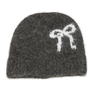 Macro detail of dark grey knitted beanie with fluffy texture and white bow pattern