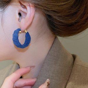 Detail of Klein blue fabric textured hoop earring with gold metallic clasp on model