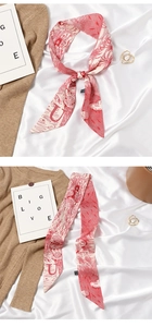 Detail of red and white silk twilly scarf tied in a bow on a soft beige knit fabric