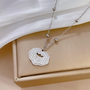 Close-up of a silver Ruyi lock pendant with Fu character on elegant silk fabric